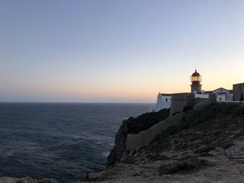 Lighthouse on building by sea against clear sky