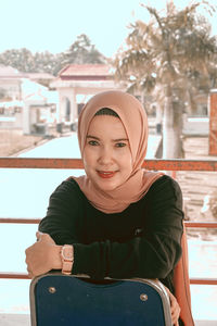 Portrait of smiling young woman standing against built structure