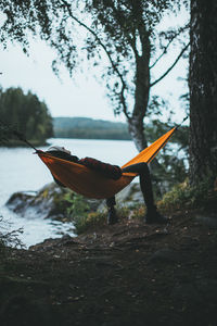 Man relaxing by lake in hammock