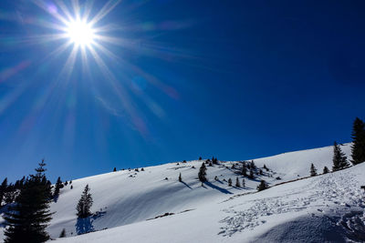 Low angle view of snowcapped mountains against blue sky