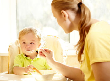 Mother feeding son at home