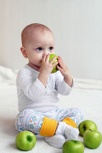 Cute baby girl sitting on apple
