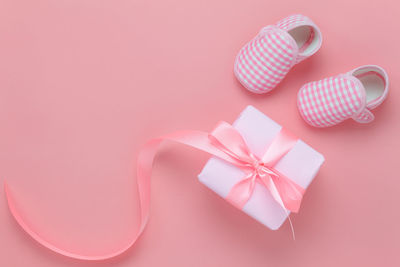 Directly above shot of baby boots with gift box over colored background