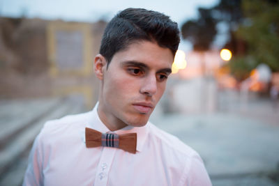 Young man looking away while standing outdoors