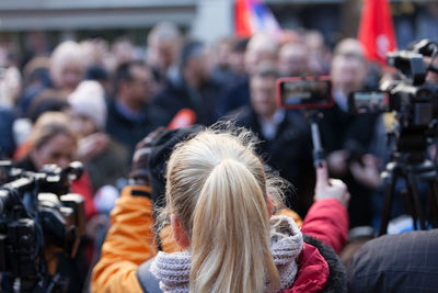 Rear view of people photographing on street