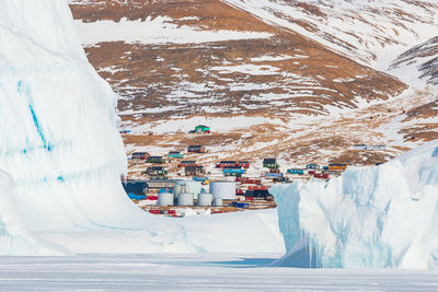 Village of qaanaaq behind icebergs, greenland.