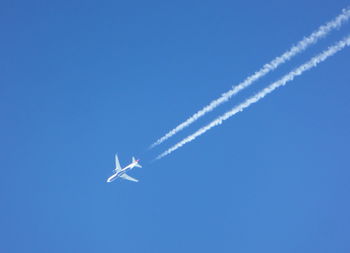 Low angle view of airplane flying against clear blue sky