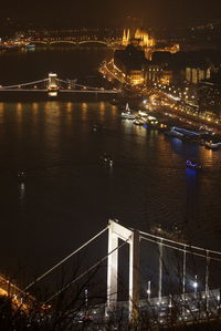 Illuminated bridge over river in city at night