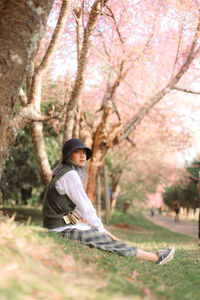 Full length of woman sitting against cherry tree