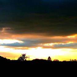 Silhouette landscape against dramatic sky during sunset