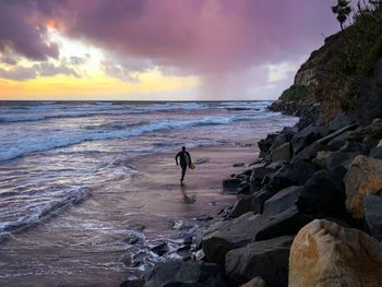 Running out into the storm to catch some waves at swamis beach, san diego, california