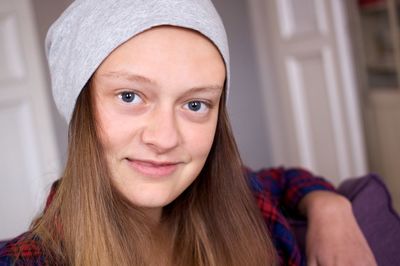 Portrait of smiling teenage girl wearing beanie at home