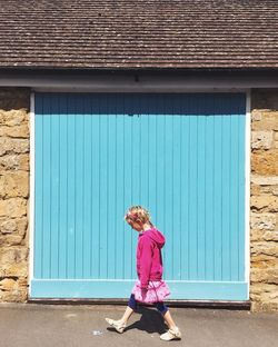 Full length of a girl standing against pink wall