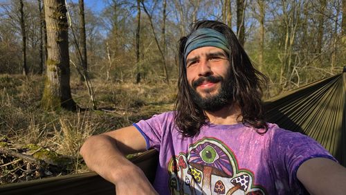 Portrait of young woman standing against trees