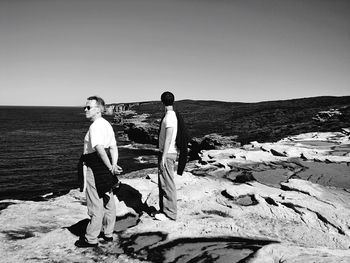 Portrait of friends standing on beach against clear sky