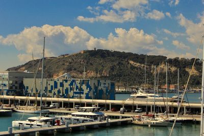 Boats moored at harbor against sky