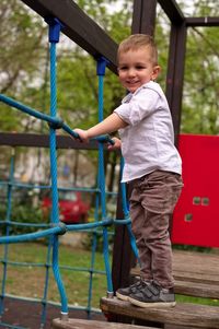 Side view of boy standing against fence