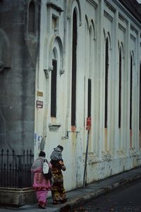 Rear view of women walking in front of building