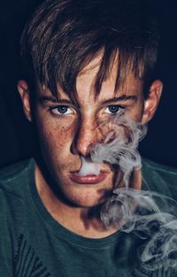 Portrait of young man blowing smoke