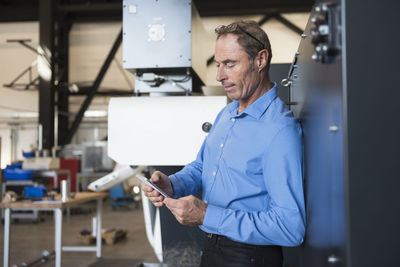 Man with cell phone on factory shop floor