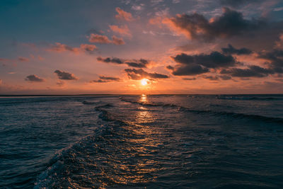 Scenic view of sea against cloudy sky during sunset