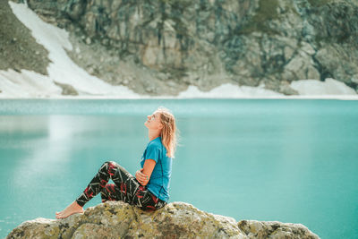 Man sitting on rock by sea