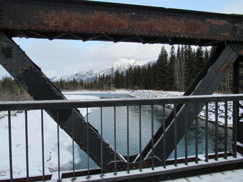 Bridge over snow covered mountains against sky