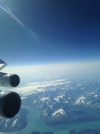 Aerial view of snowcapped mountains against blue sky