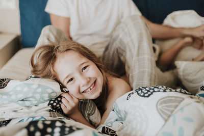 Portrait of happy girl lying on bed at home