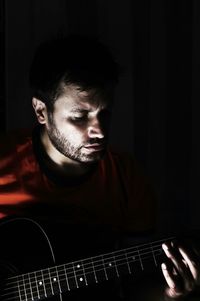 Man playing guitar in darkroom