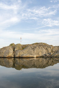 Rock formation by lake against sky