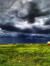 Scenic view of grassy field against cloudy sky