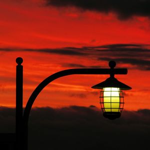Silhouette lamp against orange sky