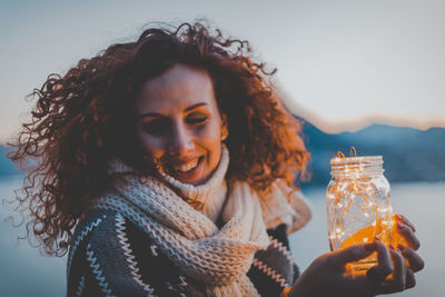 Close-up of smiling woman with ice cream against sky