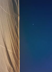 Low angle view of moon against clear blue sky