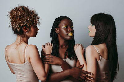 Close-up portrait of women standing against gray background