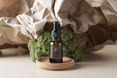 A face serum or oil in a brown dropper bottle standing on a beige table background