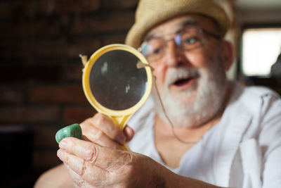 Close-up of senior man looking pebble through magnifying glass