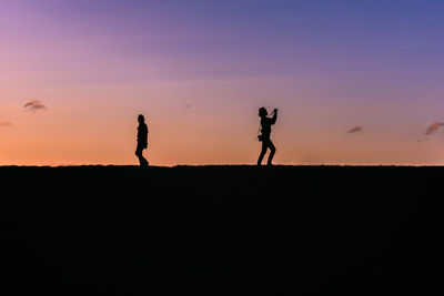 Silhouette people standing against sky during sunset