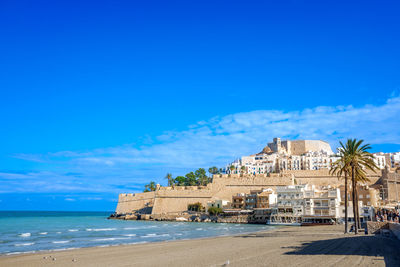 View of the city of peñiscola next to the beach and the promenade on a sunny summer day of tourism.