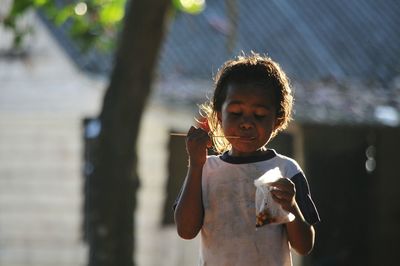 Girl eating food while standing outdoors