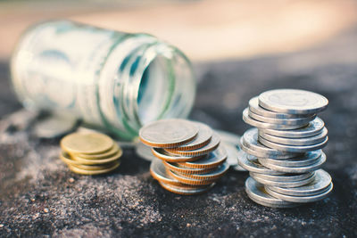 Close-up of coins with paper currency in glass jar on rock