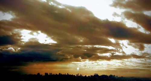 Silhouette of trees against cloudy sky