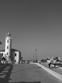 People walking in city against clear sky