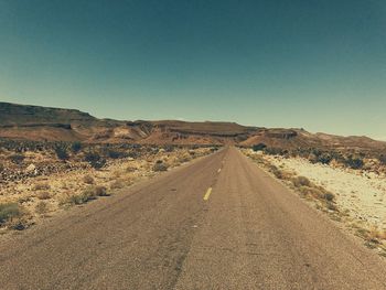 Road amidst desert against clear sky