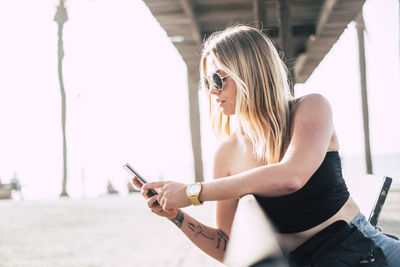 Fashionable woman using phone while sitting in city