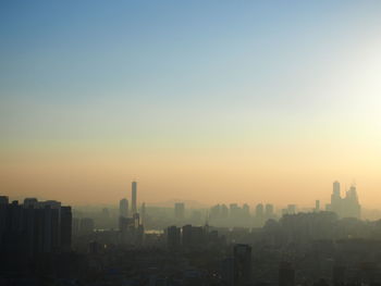 Modern buildings in city against clear sky during sunset