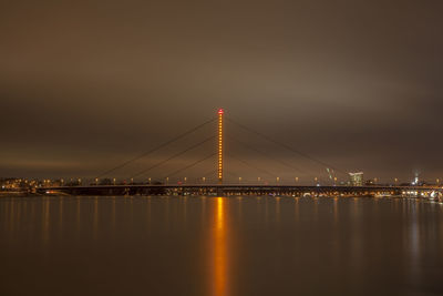 Illuminated bridge over river against sky