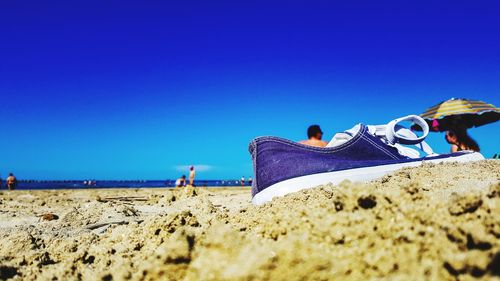 People on beach against clear blue sky