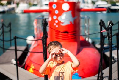 Cute boy shielding eyes while looking away at harbor